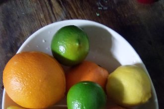 A bowl of fresh fruit including oranges, limes and apples